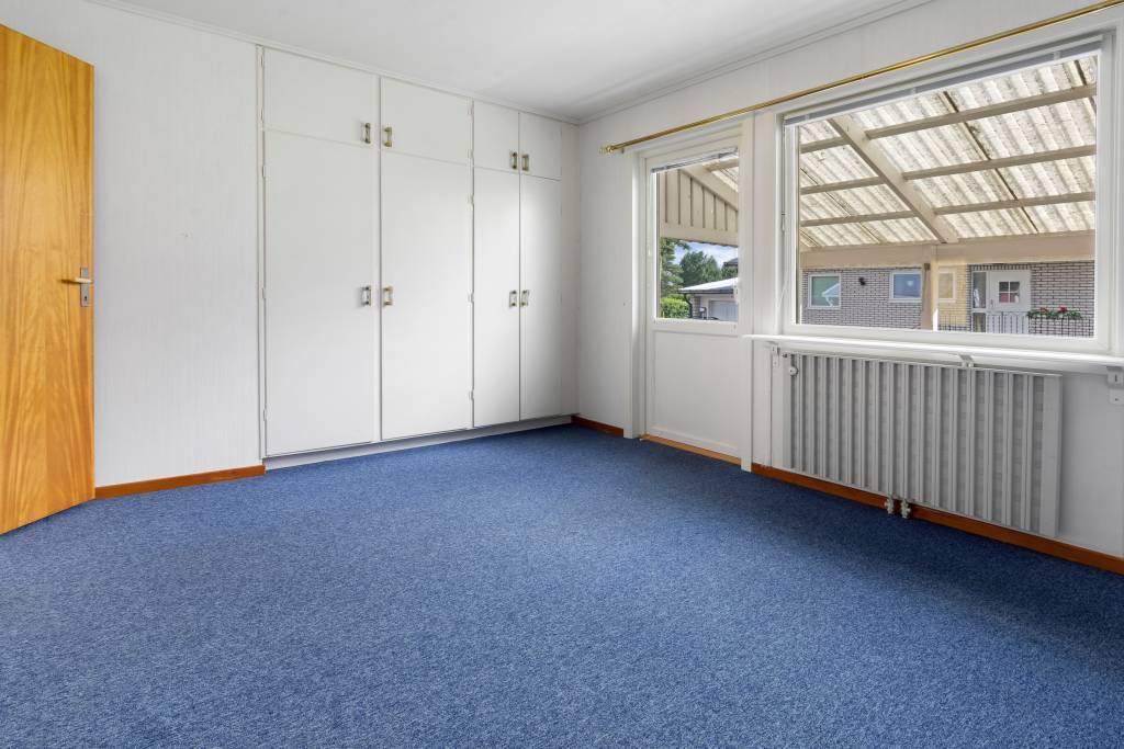 Master bedroom med heltäckningsmatta och tillgång till altan.