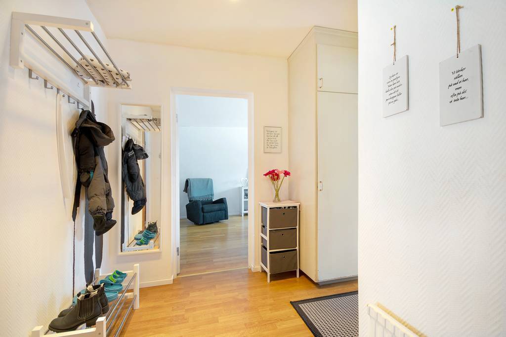 Välkomnande hall med vardagsrummet rakt fram.