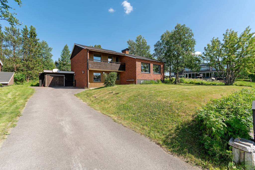 Lång uppfart med plats för flertalet bilar. Gräsmattan går runt hela fastigheten