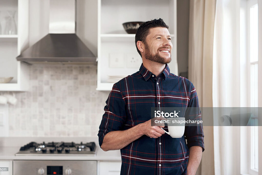 Glad man i kök med kaffekopp